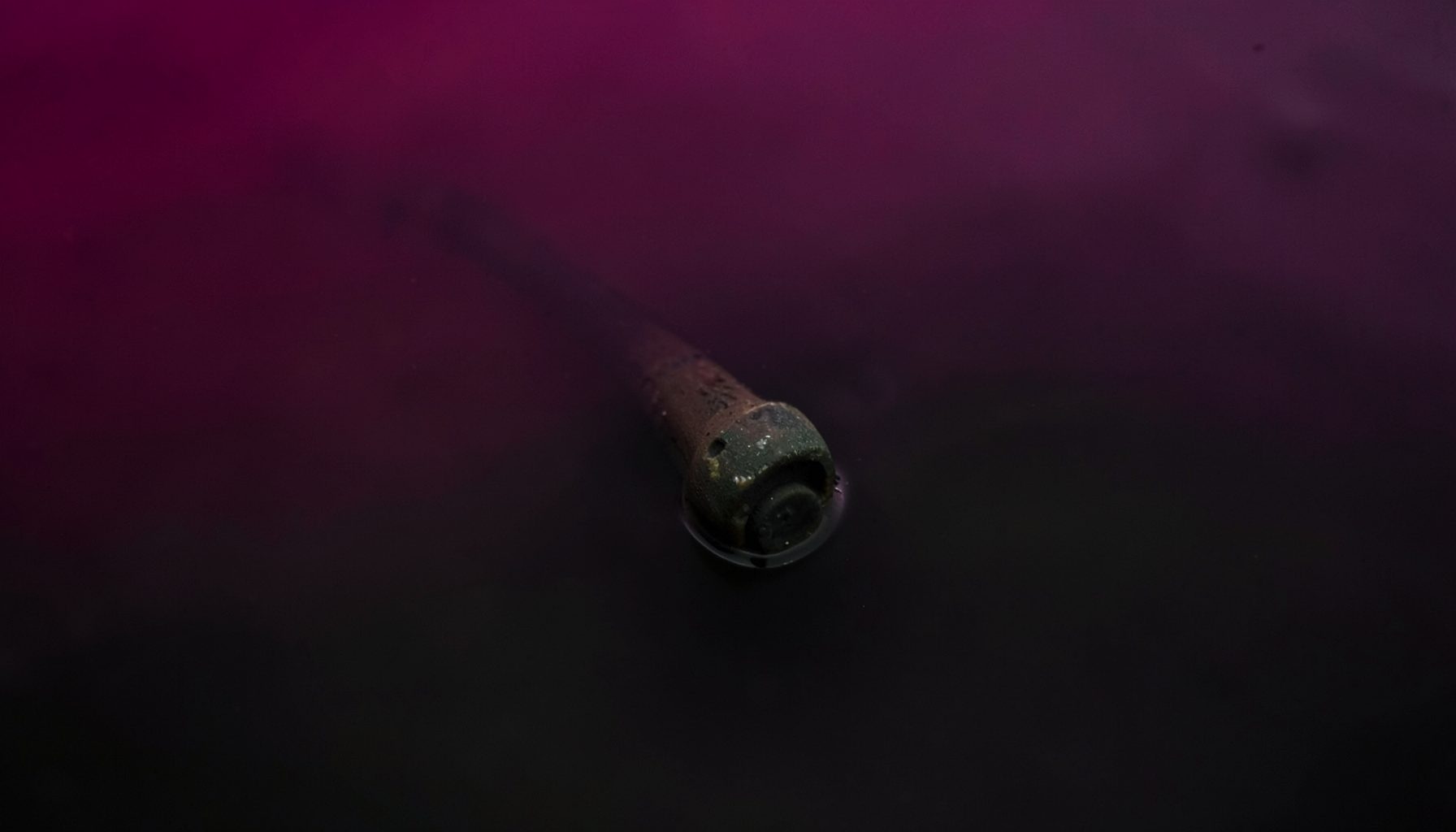 Close-up view of a rugged sensor probe submerged in murky dark water, industrial and utilitarian mood